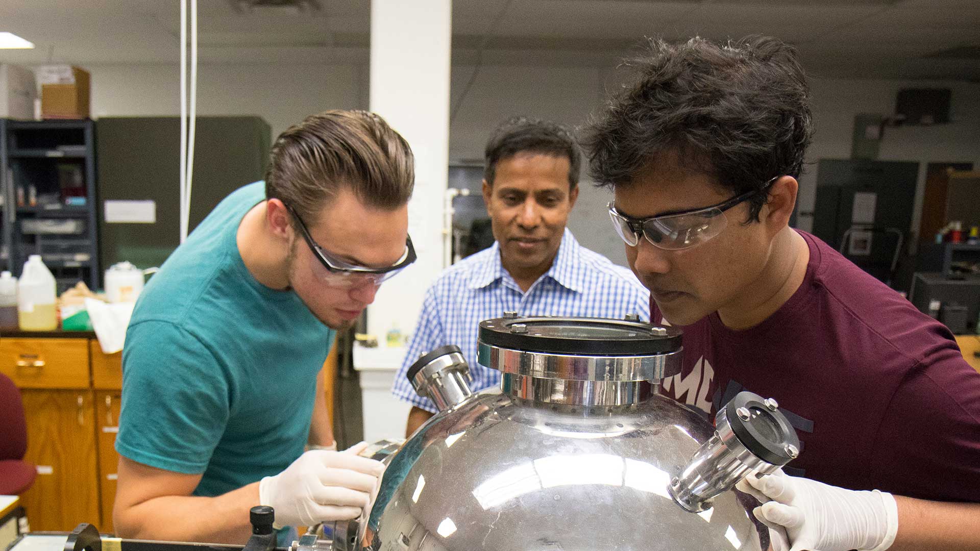 Graduate students and physics professor using pulsed laser deposition.